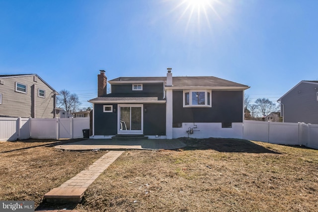 back of house featuring a patio area, a lawn, a fenced backyard, and a chimney