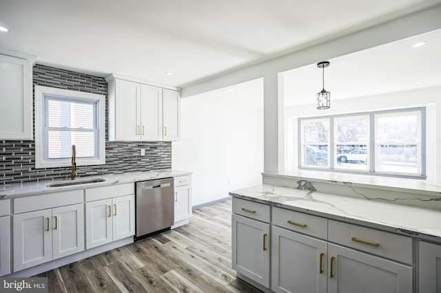 kitchen with light wood-type flooring, a sink, stainless steel dishwasher, decorative backsplash, and light stone countertops