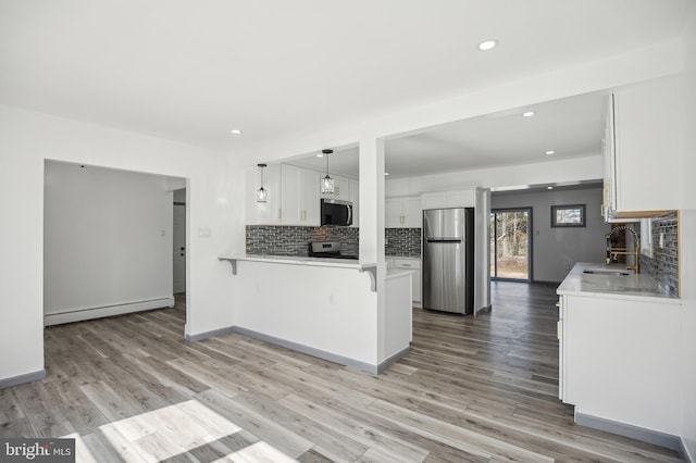 kitchen featuring a peninsula, a sink, appliances with stainless steel finishes, white cabinetry, and baseboard heating