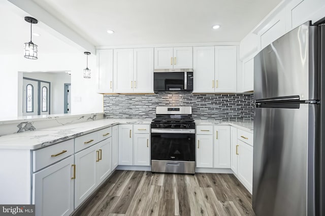 kitchen with light stone countertops, light wood finished floors, appliances with stainless steel finishes, white cabinetry, and backsplash