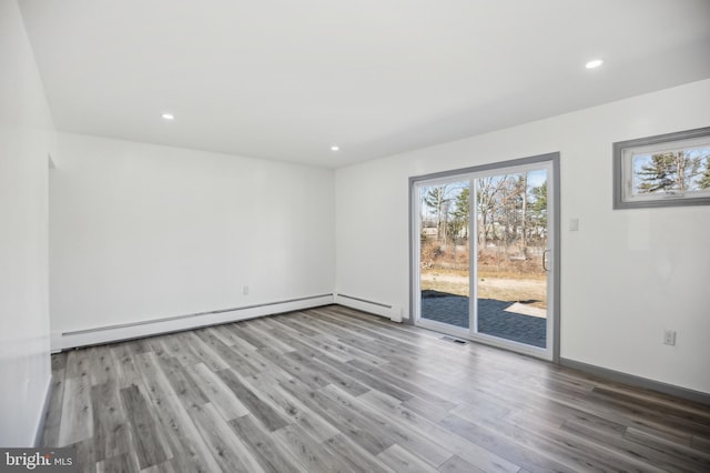 empty room featuring plenty of natural light, wood finished floors, visible vents, and a baseboard radiator