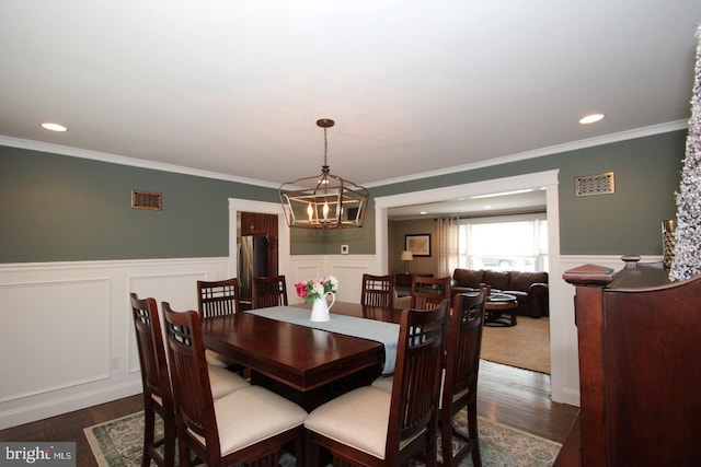 dining space with dark wood-type flooring, a wainscoted wall, and a chandelier