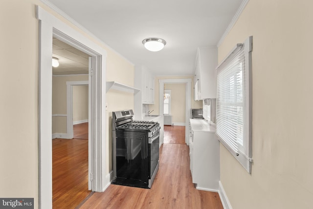 2621 2nd Rd N, Arlington, VA 22201 - kitchen with crown molding, light countertops, light wood-type flooring, gas stove, and white cabinets
