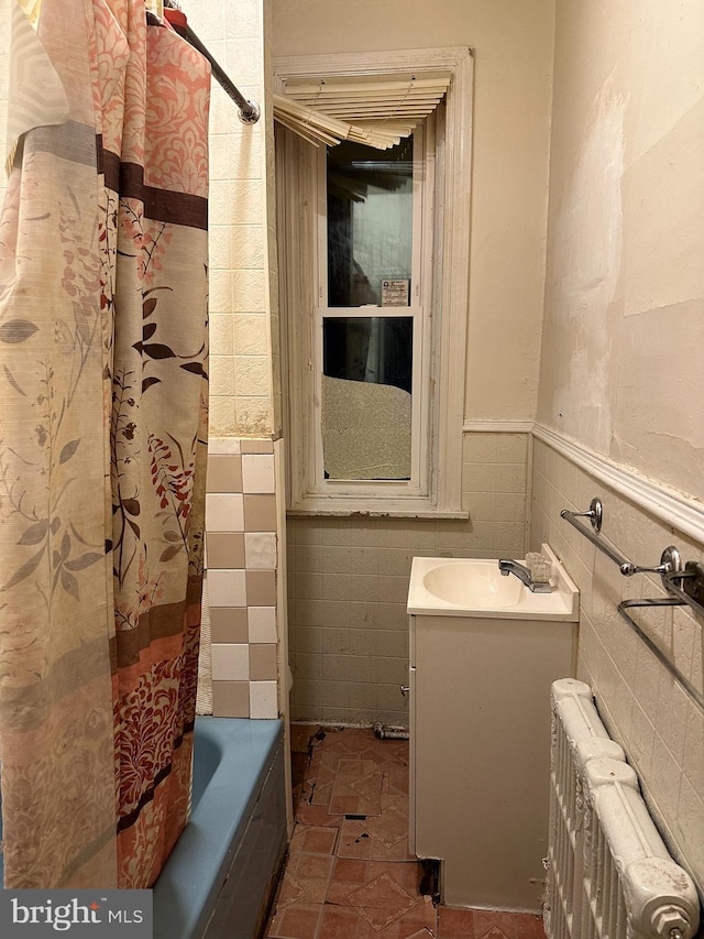 bathroom with radiator, a wainscoted wall, vanity, shower / bath combo, and tile walls