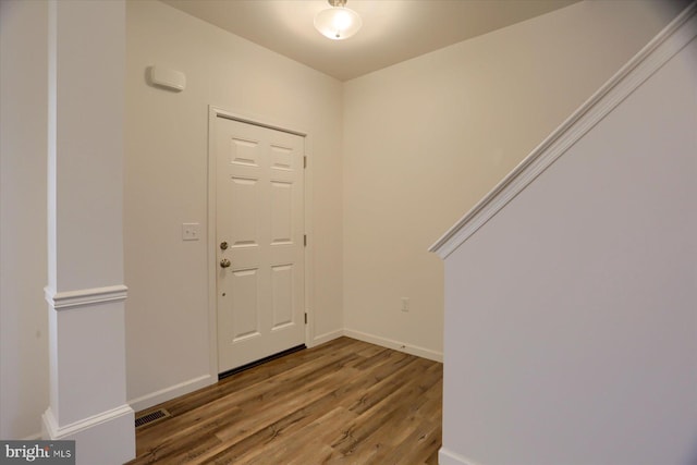 foyer entrance featuring visible vents, baseboards, and wood finished floors