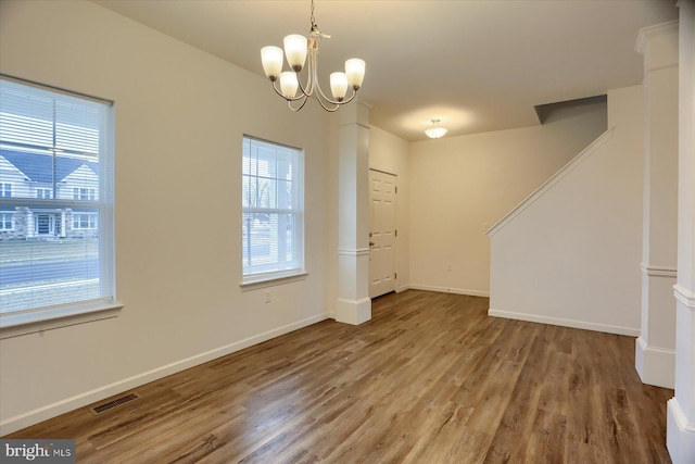 interior space featuring a notable chandelier, visible vents, baseboards, and wood finished floors