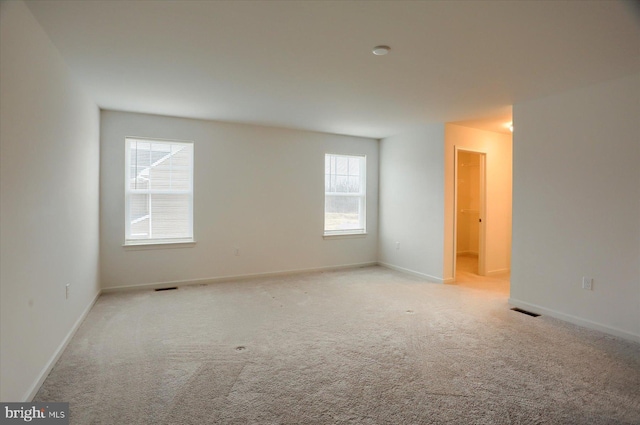 carpeted empty room featuring baseboards and visible vents