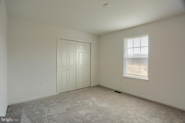 unfurnished bedroom with visible vents, carpet floors, baseboards, and a closet