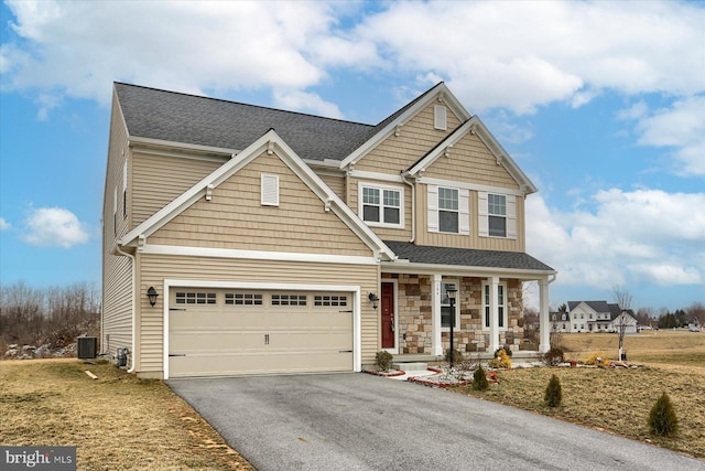 craftsman-style house featuring driveway, stone siding, a porch, a shingled roof, and central AC unit