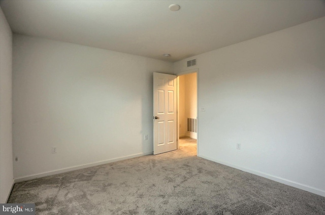 carpeted empty room with visible vents and baseboards