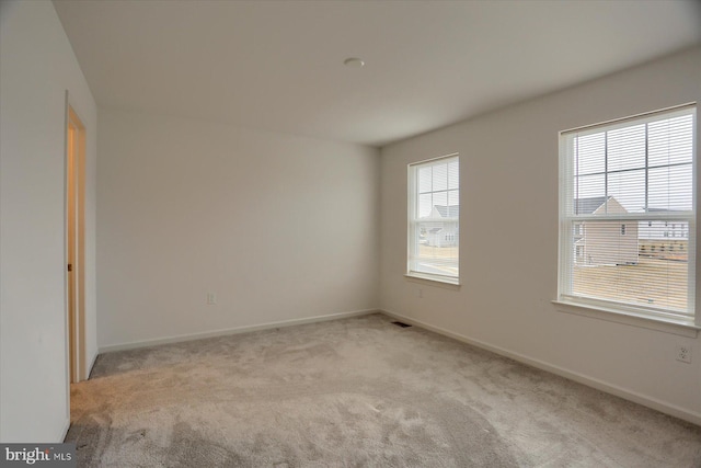 empty room with light carpet, visible vents, and baseboards