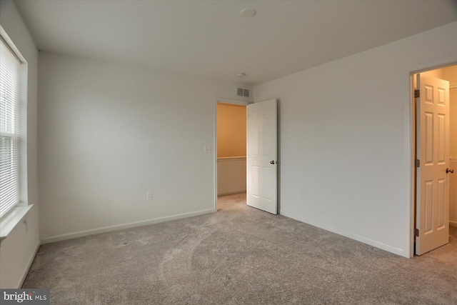 empty room with visible vents, carpet floors, and baseboards