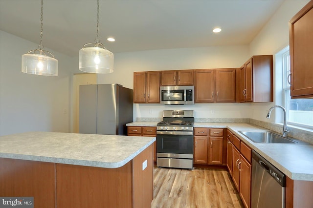 kitchen with appliances with stainless steel finishes, light wood-type flooring, light countertops, and a sink