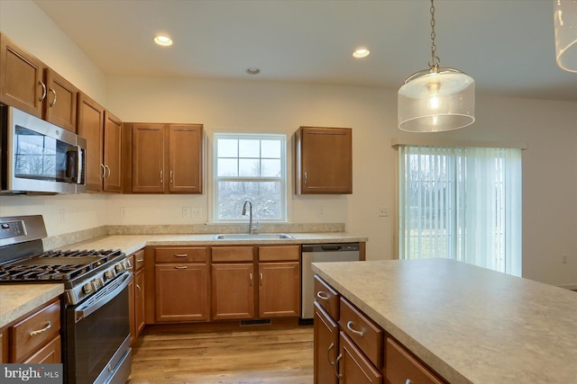 kitchen with recessed lighting, a sink, stainless steel appliances, light countertops, and brown cabinets