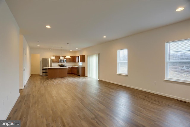 unfurnished living room with visible vents, a sink, wood finished floors, recessed lighting, and baseboards