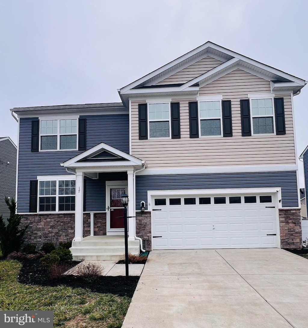 view of front of home featuring a garage, stone siding, and driveway