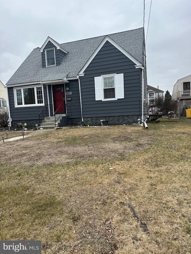 view of front of property featuring a front lawn and roof with shingles