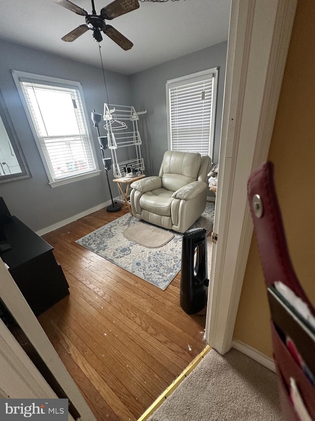 living room featuring baseboards, wood-type flooring, and ceiling fan