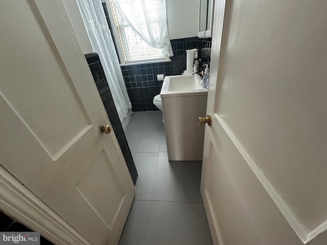 full bathroom with tile patterned flooring, tile walls, toilet, and vanity