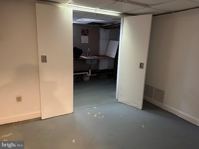 finished basement featuring a drop ceiling, visible vents, and baseboards