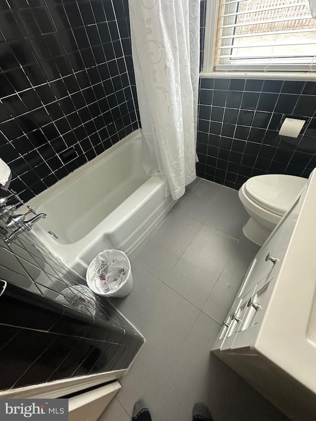 bathroom featuring tile patterned floors, shower / tub combo, toilet, and tile walls