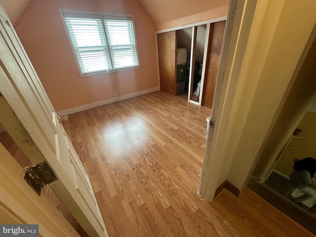 interior space featuring a closet, lofted ceiling, baseboards, and wood finished floors