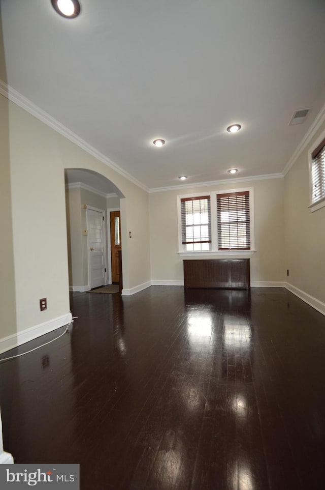 spare room with dark wood-type flooring, plenty of natural light, crown molding, and arched walkways