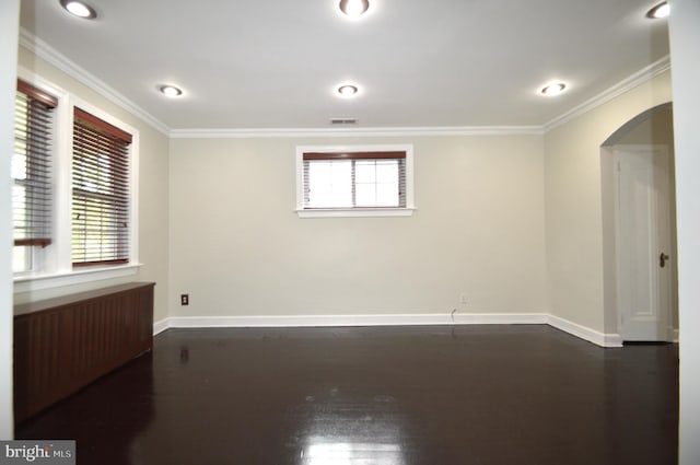 unfurnished room featuring arched walkways, visible vents, baseboards, and ornamental molding