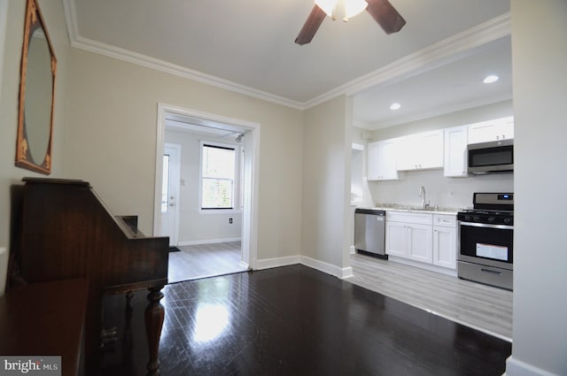 kitchen featuring crown molding, ceiling fan, dark wood-type flooring, white cabinets, and stainless steel appliances