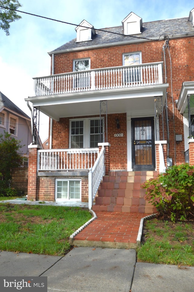 view of front facade with brick siding, a porch, and a balcony