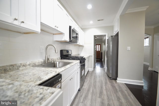 kitchen with ornamental molding, white cabinetry, stainless steel appliances, and a sink