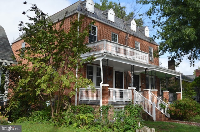 view of front of house with brick siding, covered porch, and a balcony