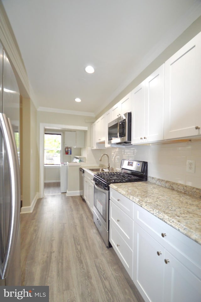 kitchen featuring a sink, crown molding, wood finished floors, and stainless steel appliances