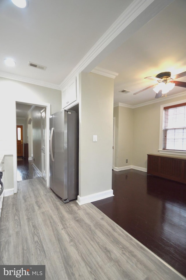 interior space with visible vents, wood finished floors, and ornamental molding