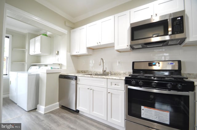 kitchen featuring backsplash, crown molding, washer and dryer, stainless steel appliances, and a sink