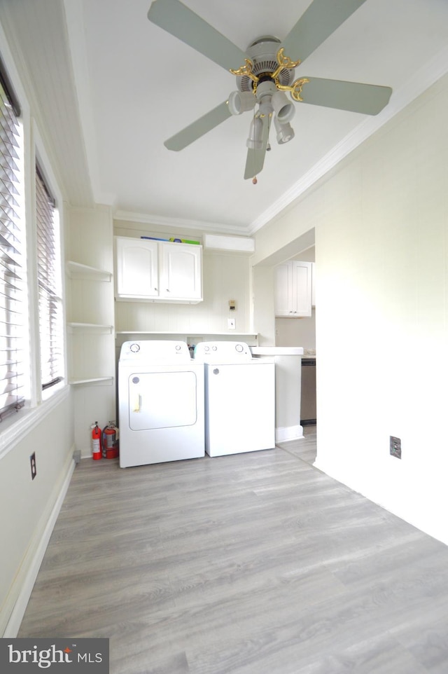 laundry room with washing machine and clothes dryer, ceiling fan, ornamental molding, light wood-style floors, and cabinet space