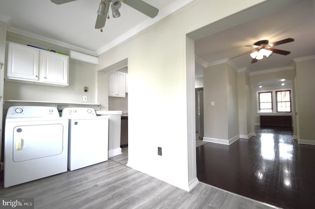 laundry room featuring a ceiling fan, cabinet space, arched walkways, crown molding, and washing machine and dryer