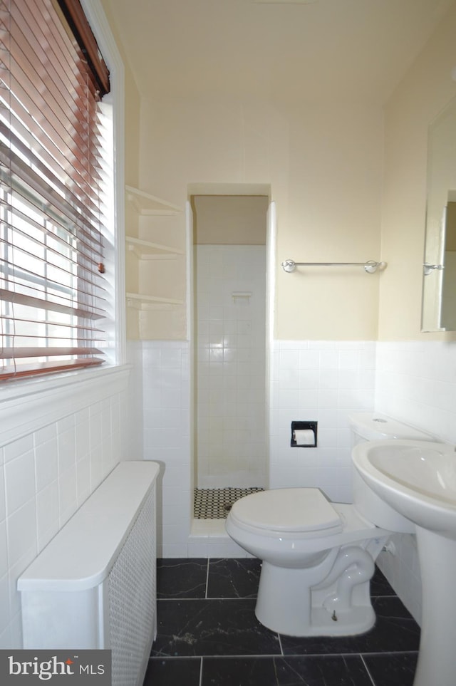 full bath featuring a wainscoted wall, a stall shower, tile walls, toilet, and marble finish floor