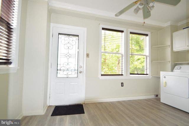 foyer entrance featuring a ceiling fan, washer / clothes dryer, crown molding, light wood finished floors, and baseboards