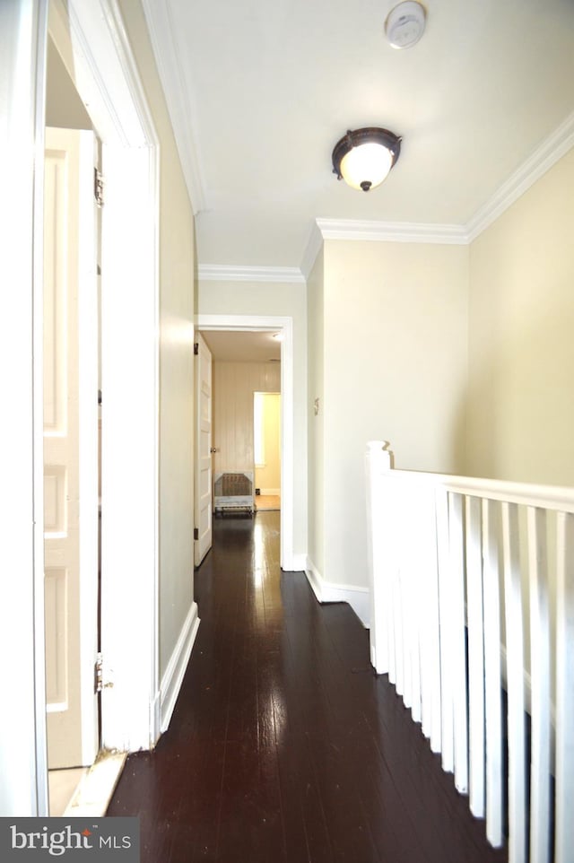 hallway with hardwood / wood-style floors, crown molding, an upstairs landing, and baseboards