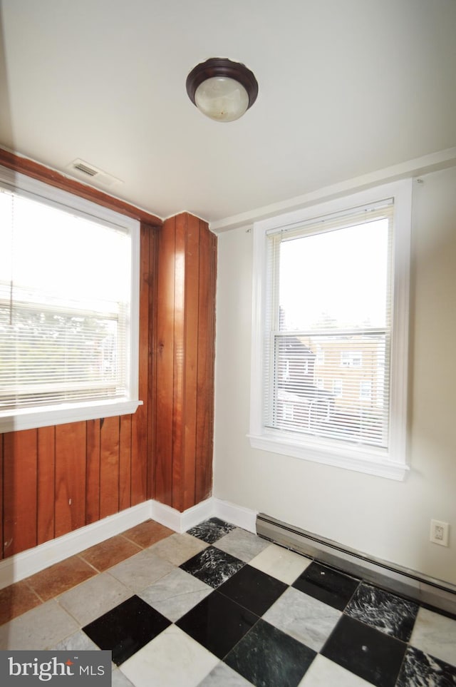 empty room with a baseboard heating unit, visible vents, and baseboards