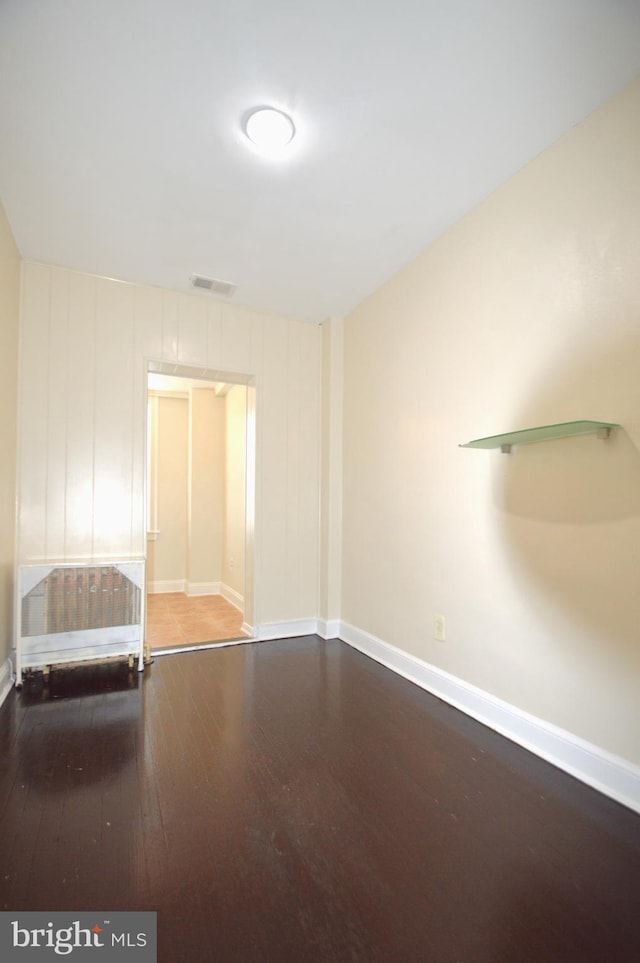 empty room featuring visible vents, baseboards, and wood finished floors