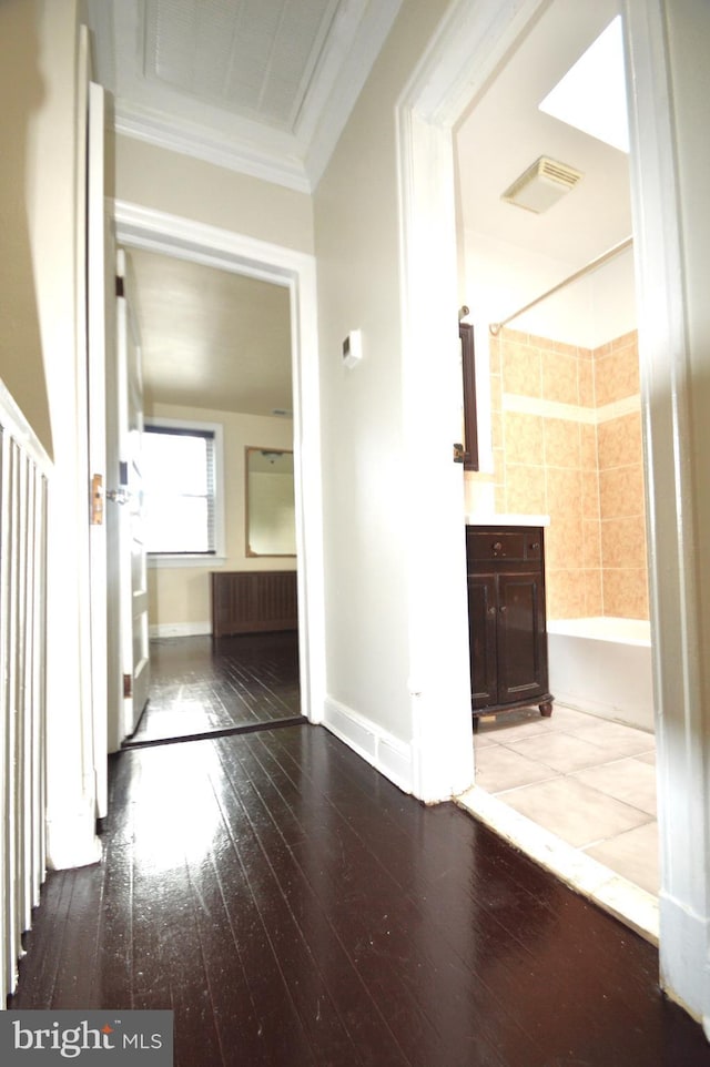 hallway with baseboards, visible vents, wood-type flooring, and ornamental molding