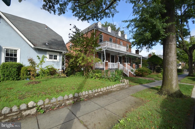 view of front of property with a front lawn, a balcony, a porch, and stucco siding