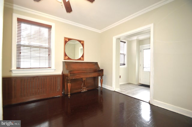 sitting room with baseboards, a ceiling fan, wood finished floors, and crown molding