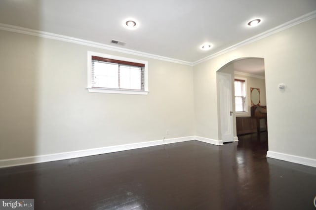 empty room featuring visible vents, crown molding, baseboards, dark wood finished floors, and arched walkways