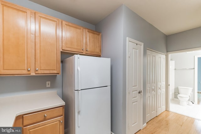 kitchen with light wood-style flooring, light countertops, and freestanding refrigerator