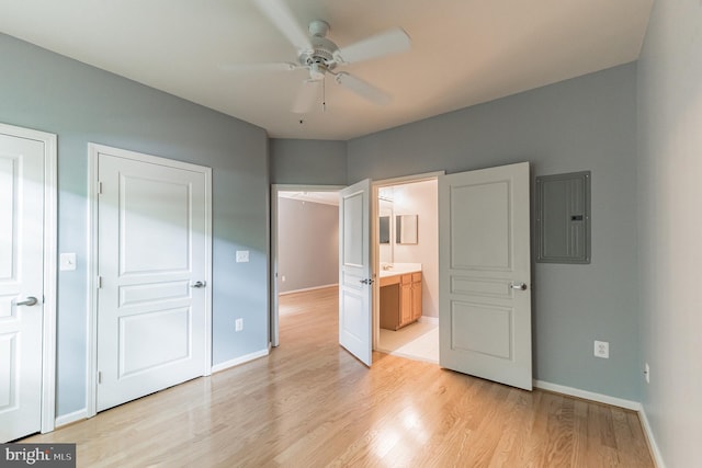 unfurnished bedroom with electric panel, light wood-style flooring, and baseboards