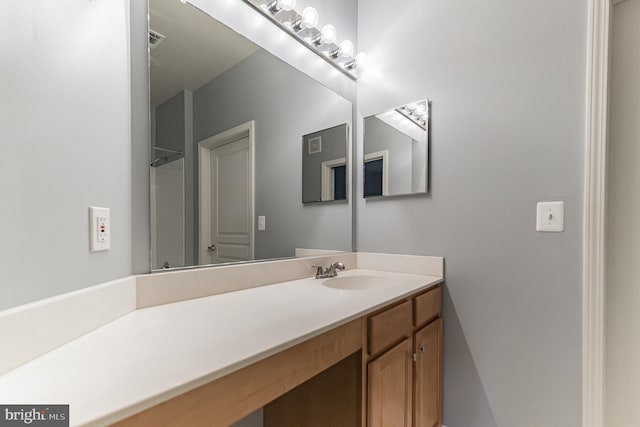 full bathroom featuring vanity, a shower, and visible vents