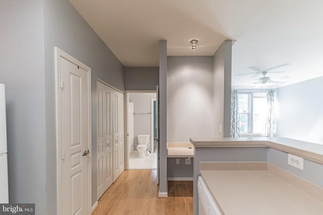 interior space with toilet, vanity, a ceiling fan, and wood finished floors